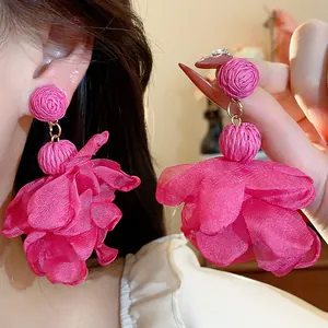 Dettaglio degli orecchini a fiore in rafia e chiffon fucsia con stile vacanza francese