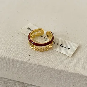 Vue détaillée d'une bague ouverte dorée avec émail bordeaux et maillons de chaîne