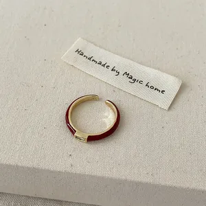 Vue détaillée d'une bague ouverte dorée avec émail rouge et pierre rectangulaire sur tissu