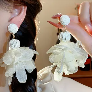 Dettaglio di eleganti orecchini in rafia bianca con grandi fiori in chiffon stile francese