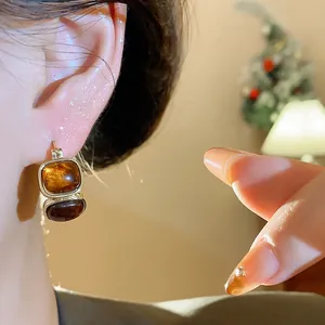 Vue détaillée de boucles d'oreilles pendantes en résine vintage sur l'oreille du mannequin