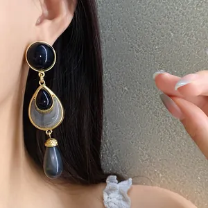Close-up detail of vintage style gold dangle earrings with elegant black resin drops