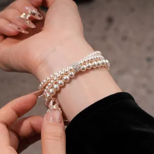 Close-up of elegant triple-strand pearl bracelet with sparkling zircon clasp detail.
