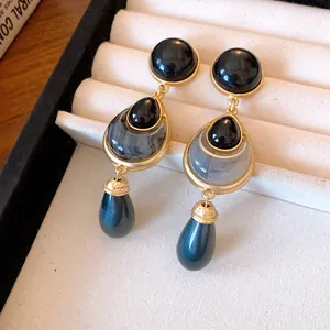 Close-up view of vintage-style dangle earrings featuring black stones and blue beads.