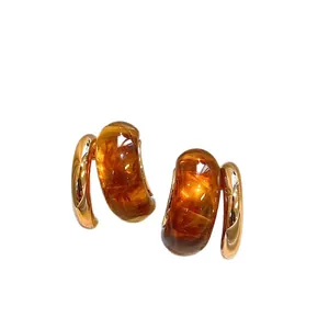 Elegantes pendientes de aro en forma de C de resina ámbar y tono dorado con textura jaspeada.
