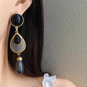 Close-up of vintage gold-tone drop earrings with black and grey marble resin details
