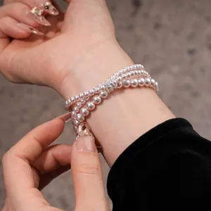 Close-up view of an elegant three-layer pink pearl bracelet with a zircon spacer on a wrist