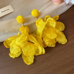 Dettaglio di orecchini a fiore in chiffon giallo vibrante con borchie in rafia