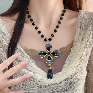 Detailed view of a vintage flower pendant necklace with black beads and beige lace top.