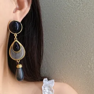 Detailed close-up of vintage gold-tone drop earrings with black and grey resin accents