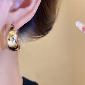 Nahaufnahme von minimalistischen, goldfarbenen, dicken Creolen mit Hochglanz-Finish