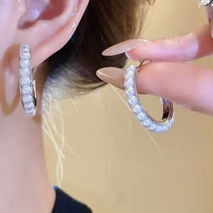 Detailaufnahme von eleganten silberfarbenen Creolen mit Reihen aus zarten weißen Perlen