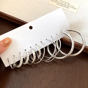 Nahaufnahme eines minimalistischen silbernen Creolen-Sets mit Perlen und Texturdetails.