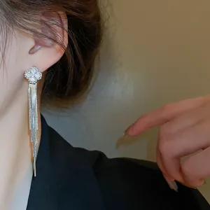 Primo piano di orecchini pendenti con nappine in argento e motivo a quadrifoglio