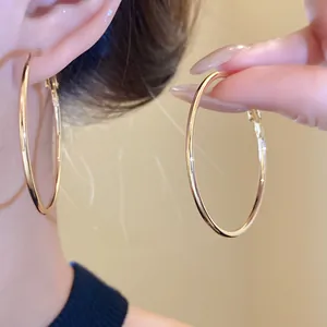 Detailaufnahme der minimalistischen goldfarbenen Creolen an Ohr und Hand präsentiert