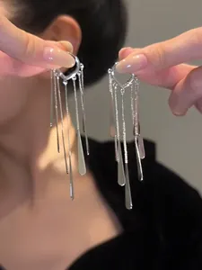 Dettaglio di orecchini a cuore argentati con lunghe nappe e gocce di metallo lucido
