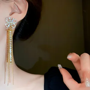 Dettaglio di eleganti orecchini lunghi a nappa con perno a quadrifoglio in strass