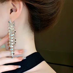 Dettaglio di eleganti orecchini a nappa lunga con paillettes geometriche argentate