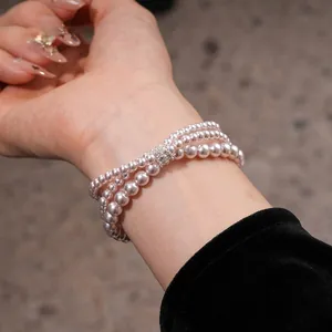 Close-up of an elegant multi-strand pearl bracelet featuring a sparkling zircon clasp