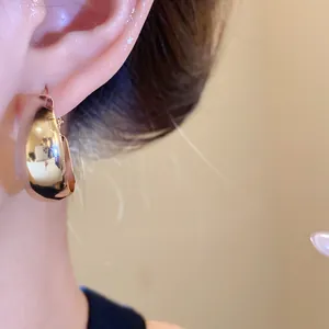 Nahaufnahme eines minimalistischen klobigen goldenen Creolen-Ohrrings