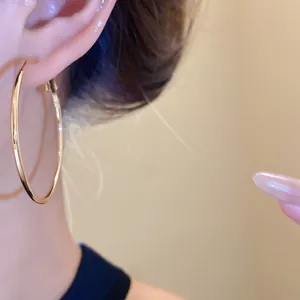 Detaillierte Nahaufnahme eines minimalistischen großen goldenen Creolen-Ohrrings am Ohr