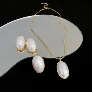 Elegant oval pearl jewelry set featuring gold-plated necklace and earrings on mirror