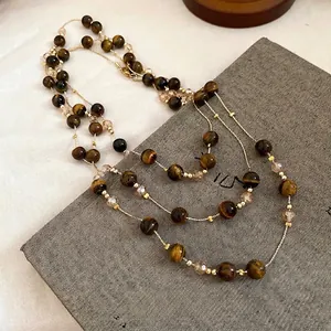 Vintage tiger's eye beaded necklace with gold accents on textured grey background.