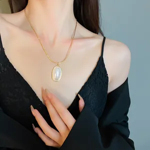 Elegant gold plated necklace with a minimalist oval white pearl pendant on a model