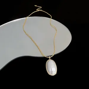 Elegant 14k gold plated chain necklace featuring a large oval pearl pendant on a mirror