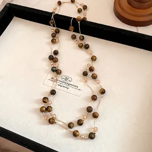 Retro tiger's eye beaded necklace with gold-tone accents on a beige display background