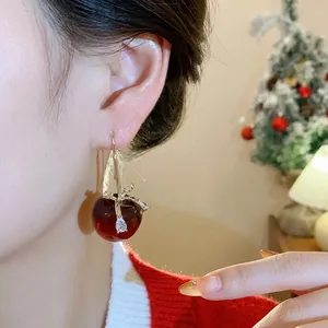 Elegante Harz-Apfel-Ohrringe mit Zirkon-Schleife an einem asiatischen Model.