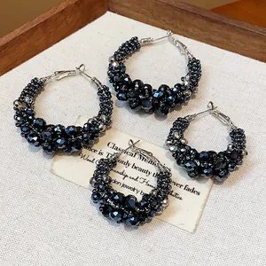 Close-up of vintage black faceted glass beaded hoop earrings on rustic background