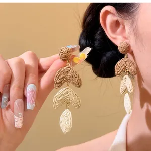 Detailed close-up of handmade raffia woven earrings featuring a layered bohemian design