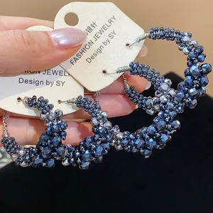 Detail view of vintage hoop earrings featuring dark blue faceted glass beads and silver pins