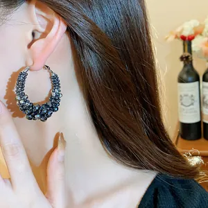 Close-up view of vintage hoop earrings with dark grey irregular glass beads on a model.