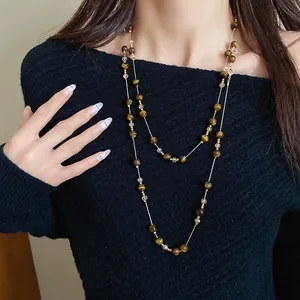 Detailed view of layered tiger eye stone beaded necklace styled on black knit sweater