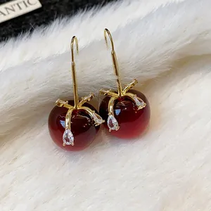 Detailansicht eleganter roter Apfelohrringe aus Harz mit funkelnder Zirkon-Schleife