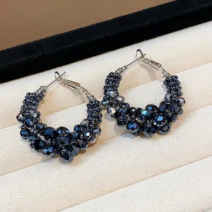 Close-up of vintage hoop earrings with dark navy faceted glass beads in a clustered design.