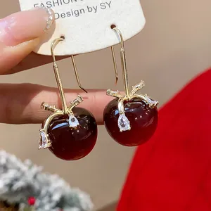 Detailansicht der roten Harz-Apfel-Ohrringe mit eleganten zirkonbesetzten Schleifendetails.