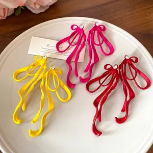 Elegant matte bow earrings with sparkling crystal studs in yellow, pink, and red.
