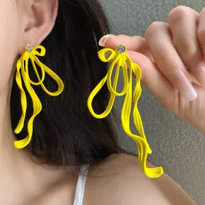 Vibrant yellow bow-knot earrings with sparkling rhinestone detail on an Asian model