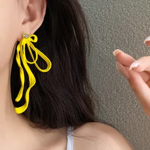 Detailed close-up showing vibrant yellow ribbon bow earring with a sparkling rhinestone stud