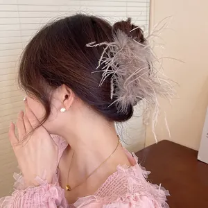 Elegant light grey feather hair claw clip shown in detail on a woman's bun hairstyle