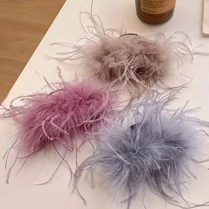 Detail shot of three elegant ostrich feather hair claws in soft pastel shades on white table
