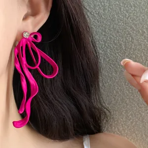 Detail view of a stylish vibrant pink ribbon bow earring with a sparkling rhinestone