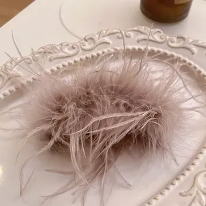 Elegant soft pink feather hair claw clip displayed on vintage white decorative plate