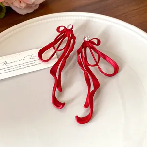 Detailed view of red matte bow earrings with crystal studs on a ceramic plate
