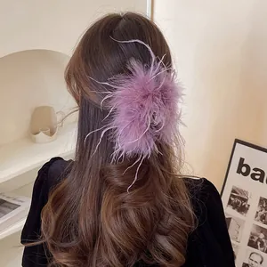 Elegant purple ostrich feather hair claw clip styled on long wavy brown hair for women