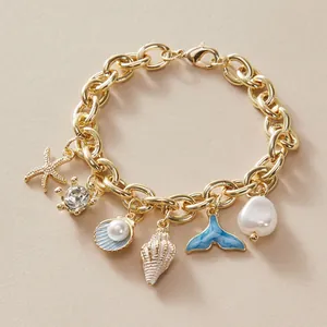 Detailed view of a vintage gold charm bracelet with ocean-themed pendants and pearls