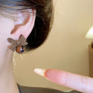 Primo piano di un orecchino a fiocco floccato marrone con una perla fantasia elegante